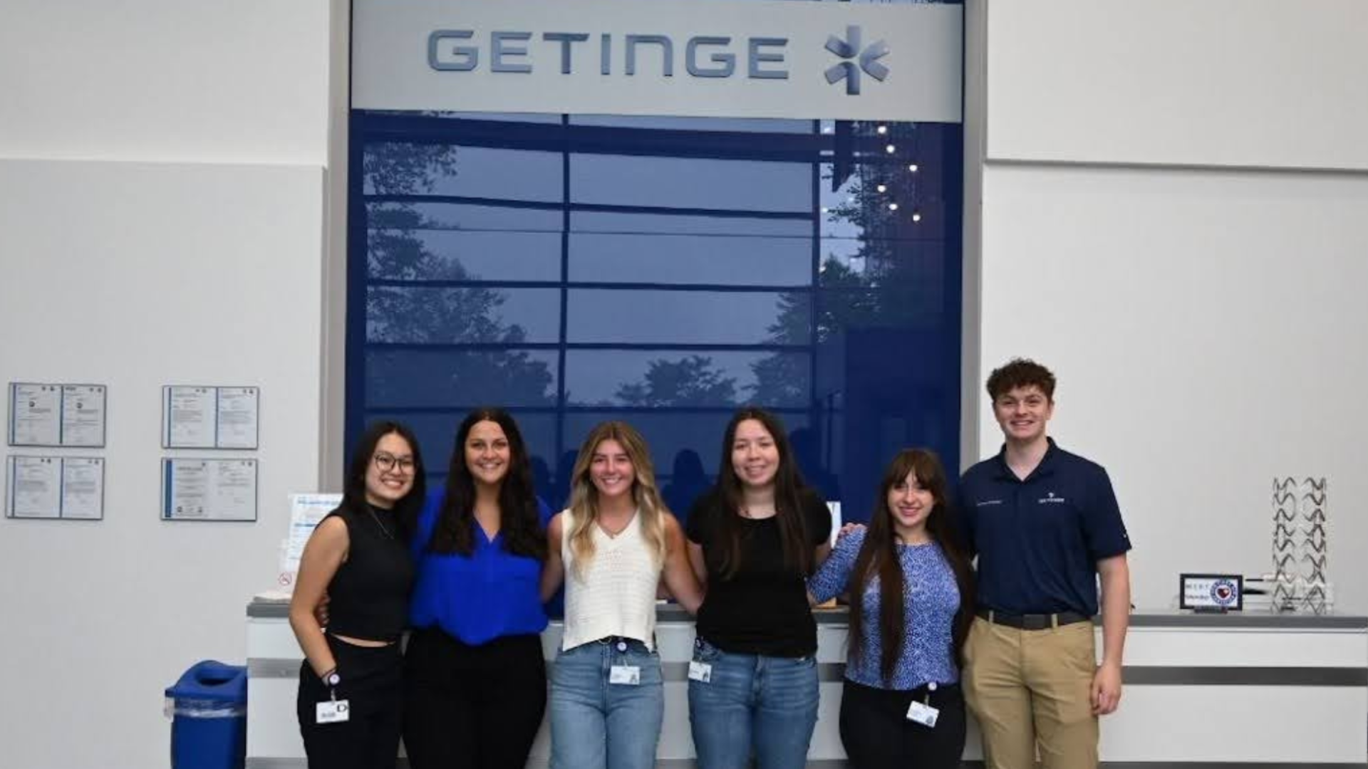 Kristina stands with interns by the Getinge sign.