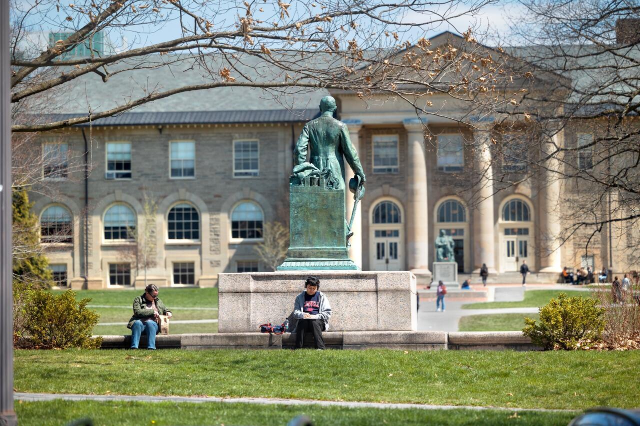 Students enjoy the sun on the Arts Quad by the Ezra Cornell Statue.