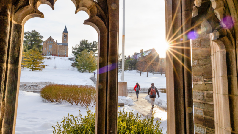 Students walk from McFaddin Hall towards the snow-covered slope.