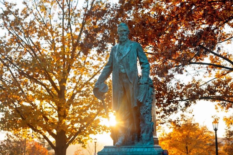 The Ezra Cornell Statue in the Arts Quad during an autumn sunset.