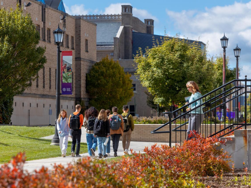 Students pass Martha Van Rennsellear on a warm fall day.