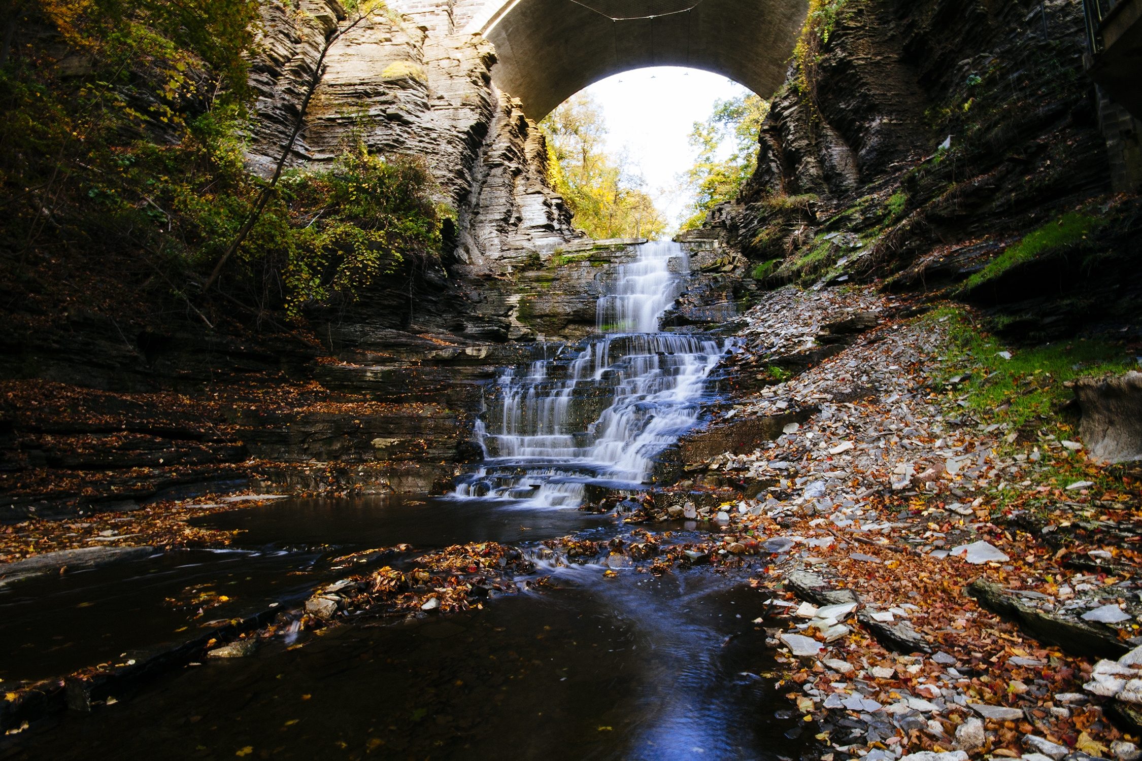 The Cascadilla Creek waterfall under the College Avenue Stone Arch Bridge, in fall.